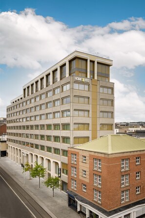Un hôtel à plusieurs étages, doté d’une façade beige, de nombreuses fenêtres par étage et d’un toit plat.