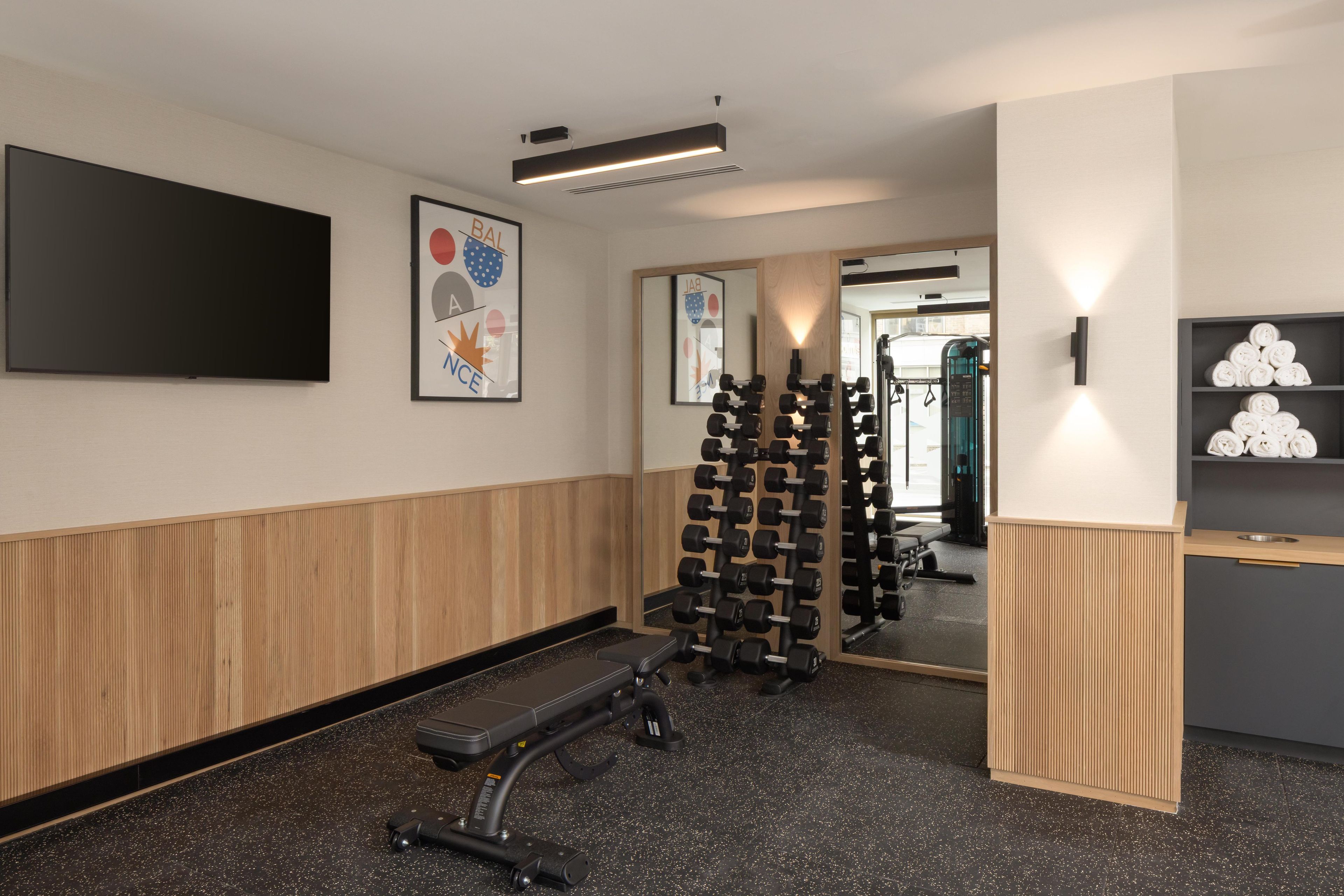 Une salle de sport équipée d’un banc, d’haltères et d’un tapis de course.