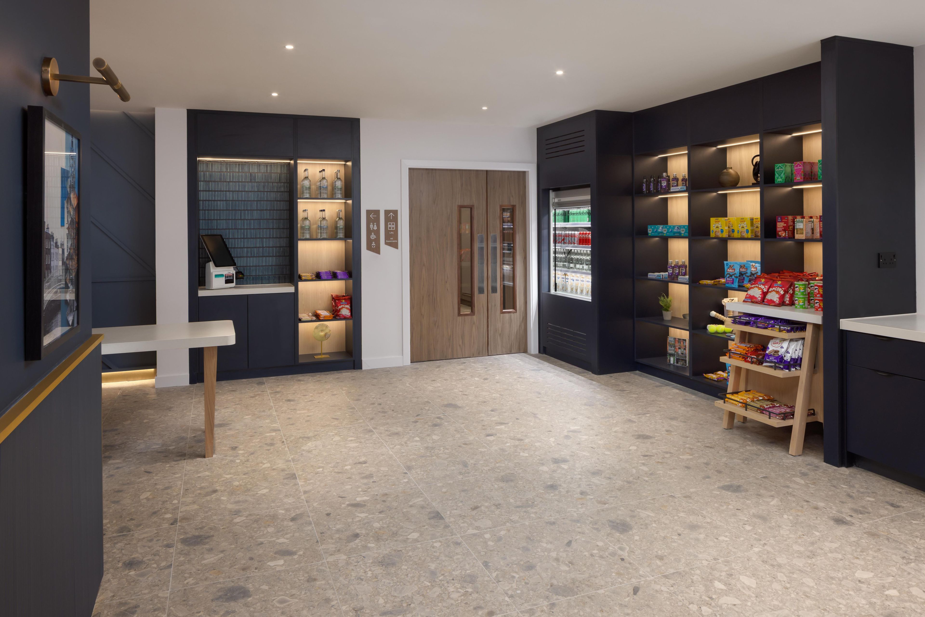 Un interno moderno con una reception, una macchina per distributore e scaffali pieni di snack e bevande.