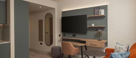 Una habitación de hotel moderna con una cama, un escritorio, una silla, un televisor y un sofá.