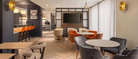 Una habitación de hotel moderna con zona de comedor, televisor y cocina.