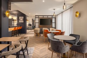A modern hotel room with a dining area, a TV, and a kitchen. - Home2 Suites By Hilton Dublin City Centre (Dublin)