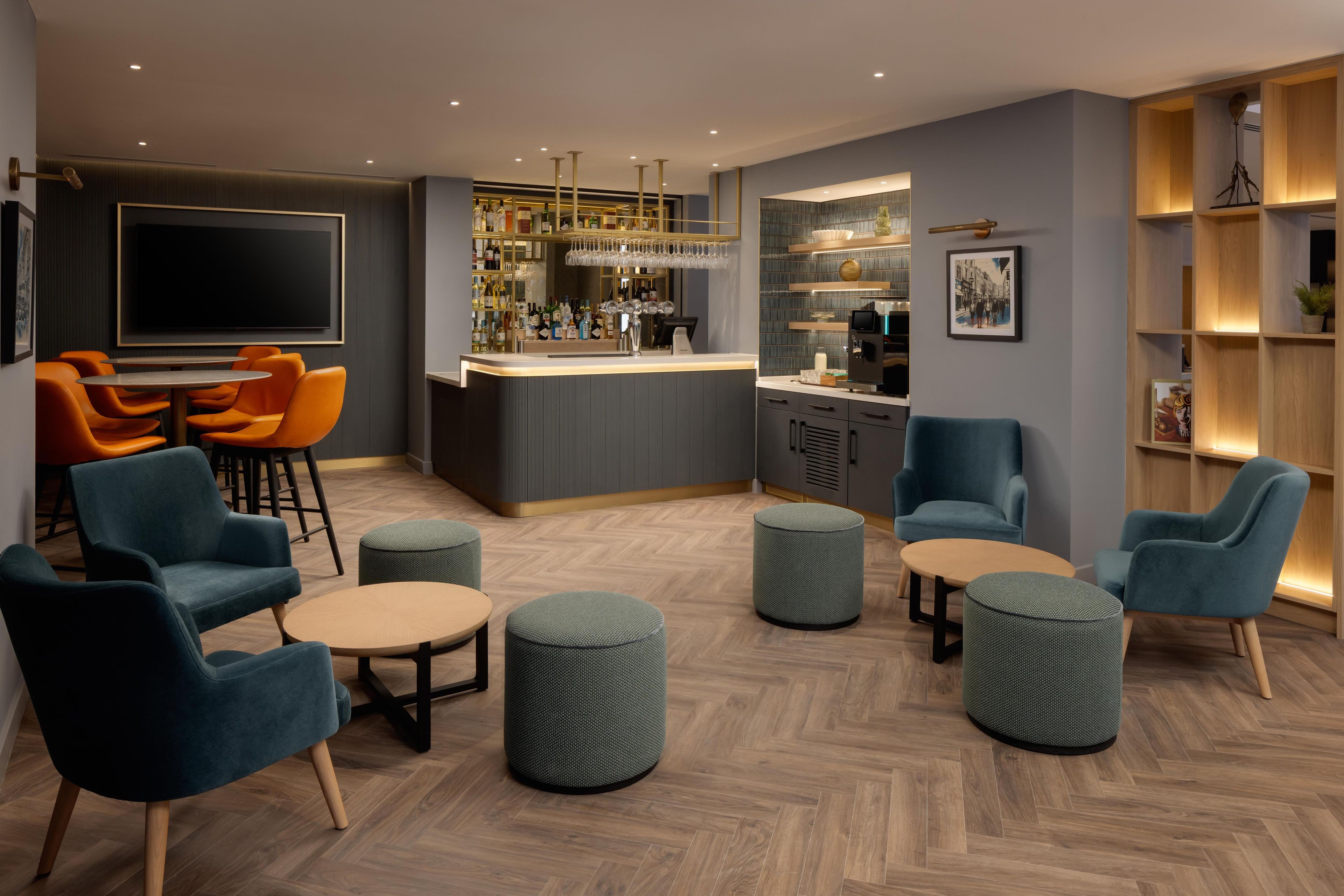 A modern lounge area with seating, a bar, and a television.
