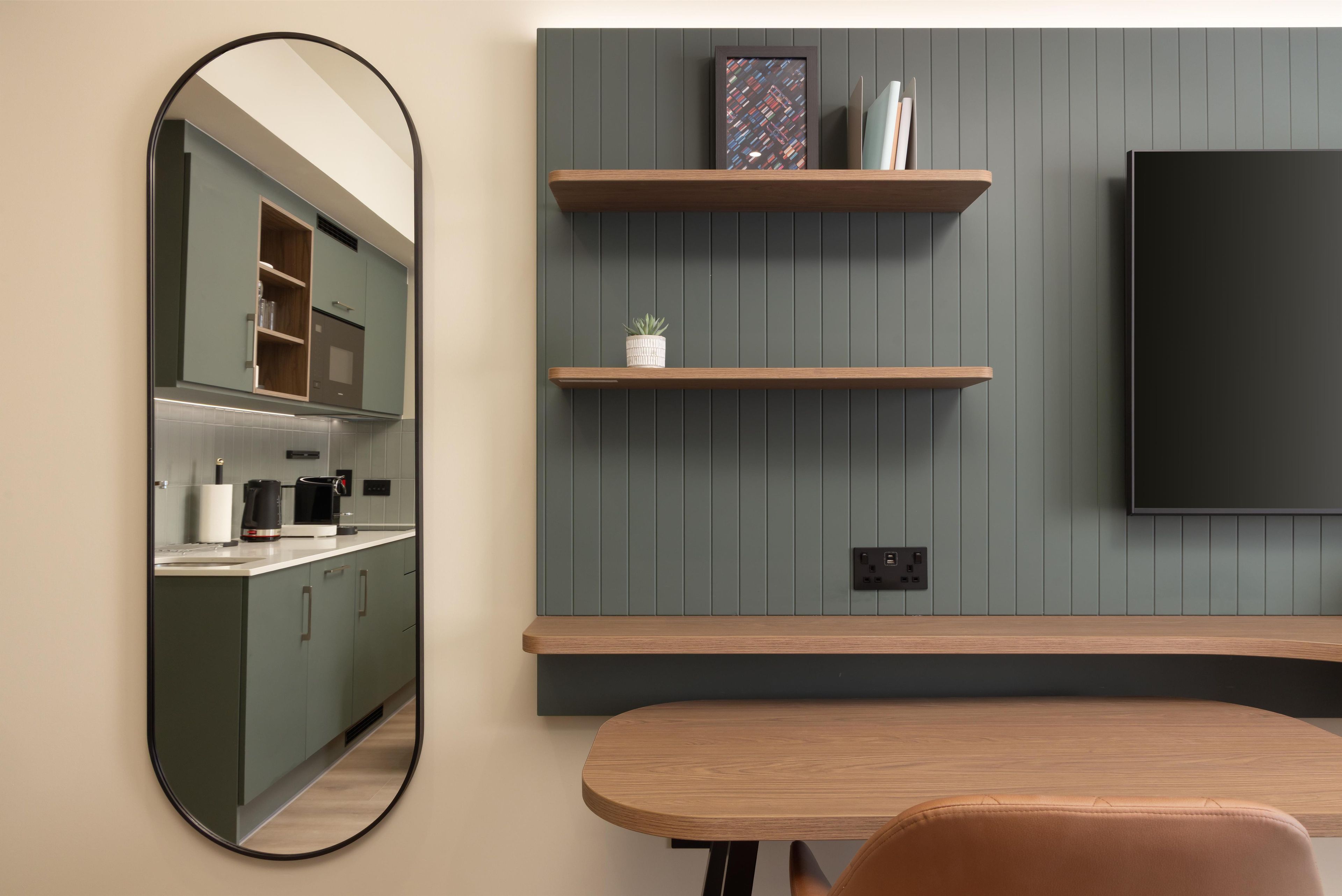 A modern kitchen with a built-in oven, a coffee maker, and a kettle on the counter.