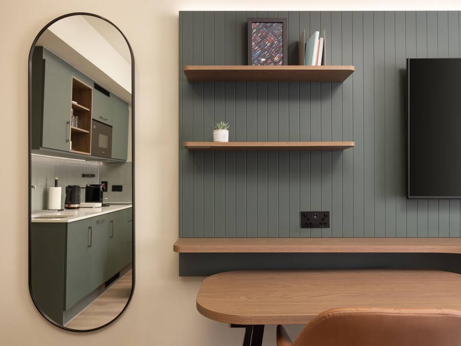 A modern kitchen with a built-in oven, a coffee maker, and a kettle on the counter.