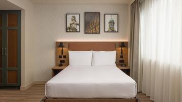 A neatly made bed with a wooden headboard, two bedside tables with lamps, and three framed pictures on the wall.
