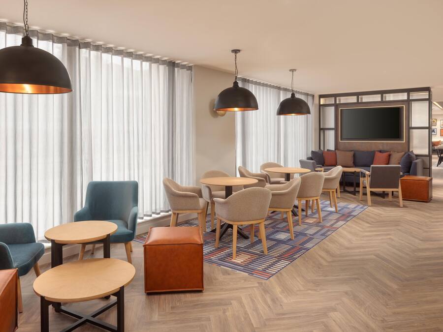 Een moderne hotelentree met een zithoek, grote ramen en een flatscreen televisie.