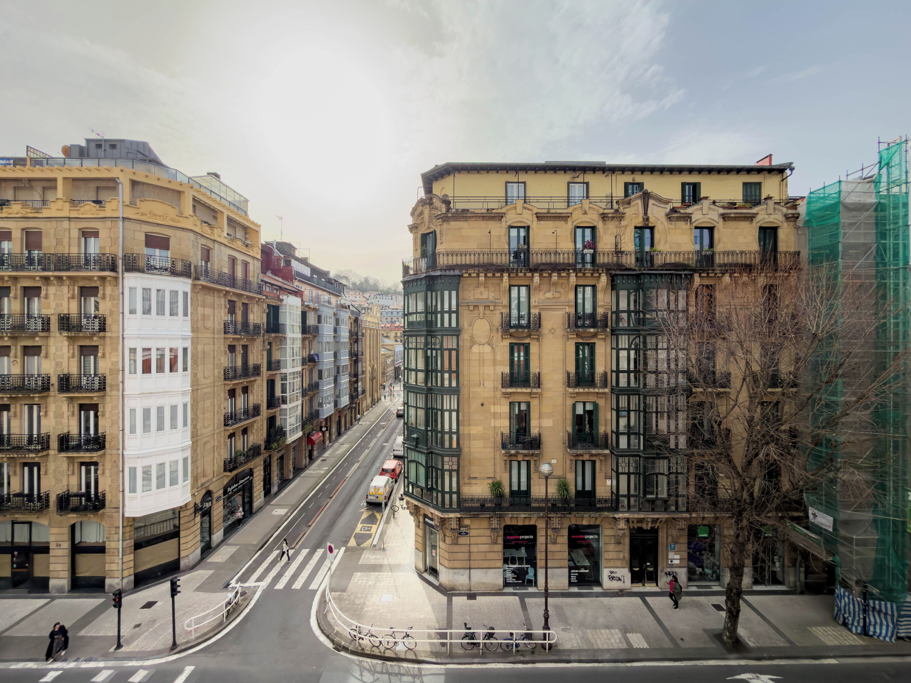 A street view with buildings, a crosswalk, and a few pedestrians.