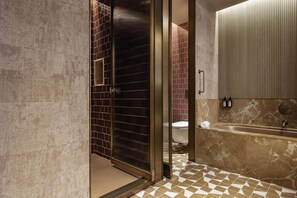 A bathroom with a glass shower door, a marble sink, and a tiled floor. - Hotel Palacio Bellas Artes San Sebastián, Curio Collection (San Sebastian)