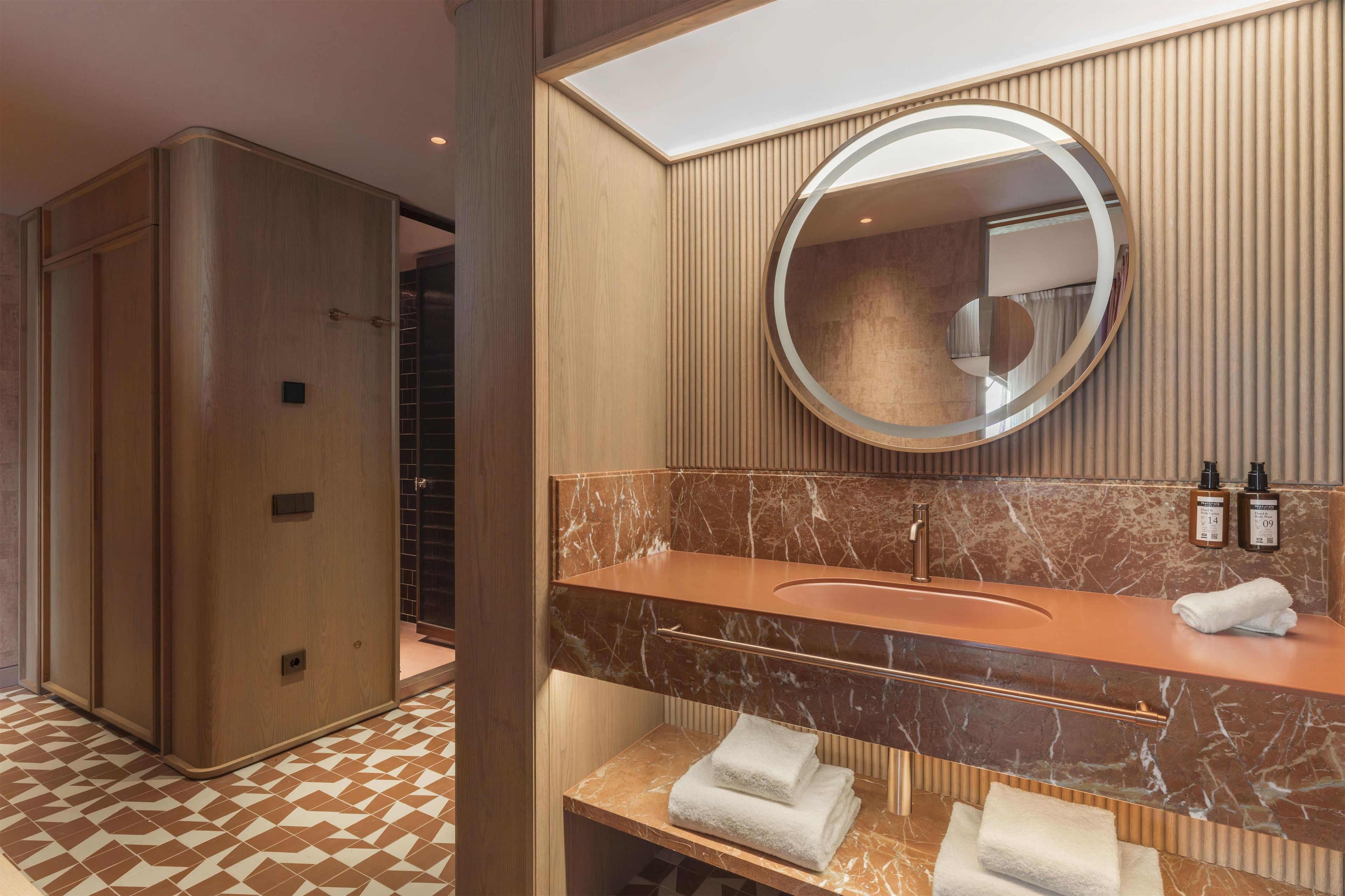 A modern bathroom with a marble sink, a large mirror, and a towel rack.
