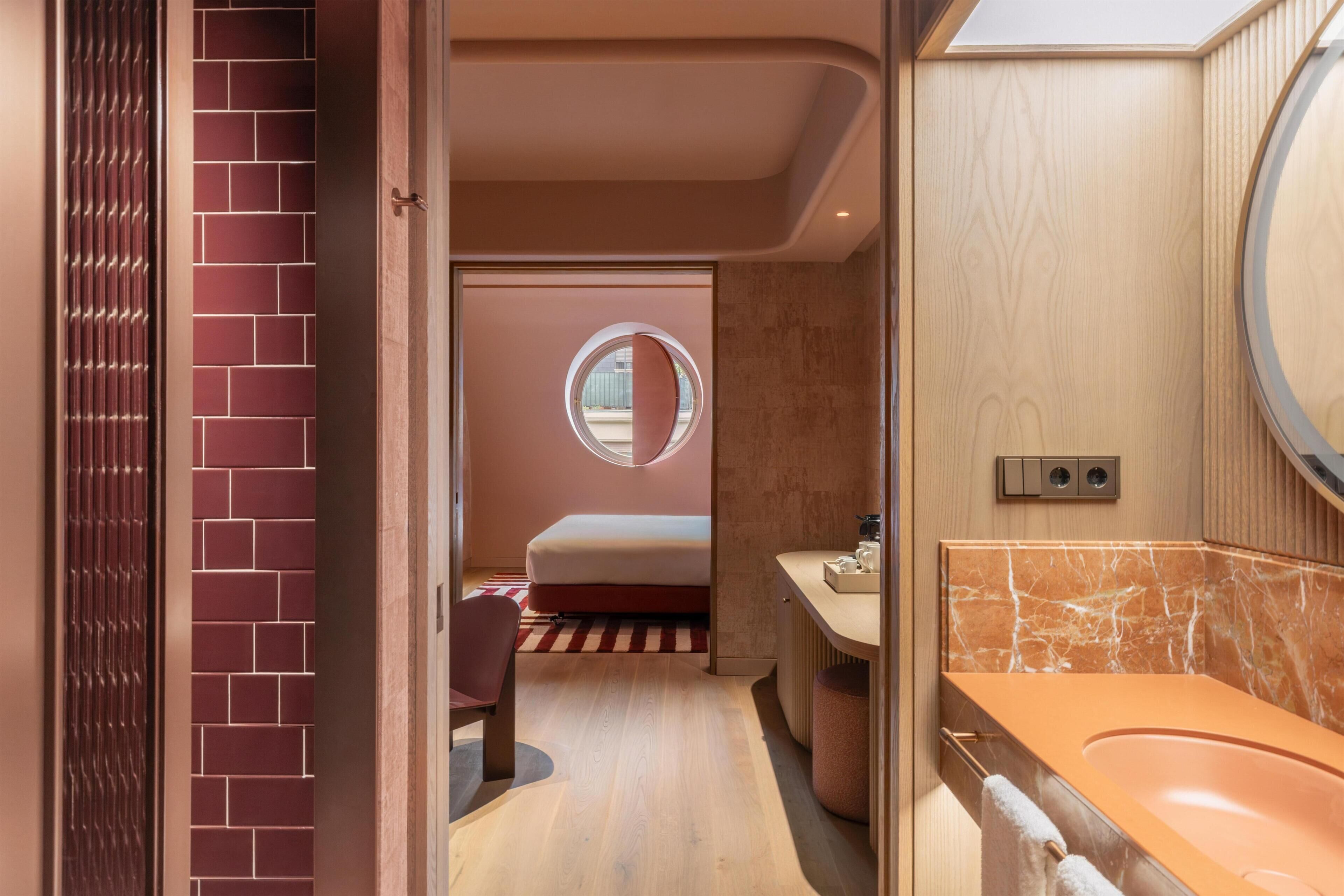 A modern bathroom with a marble sink, a round mirror, and a wooden vanity.