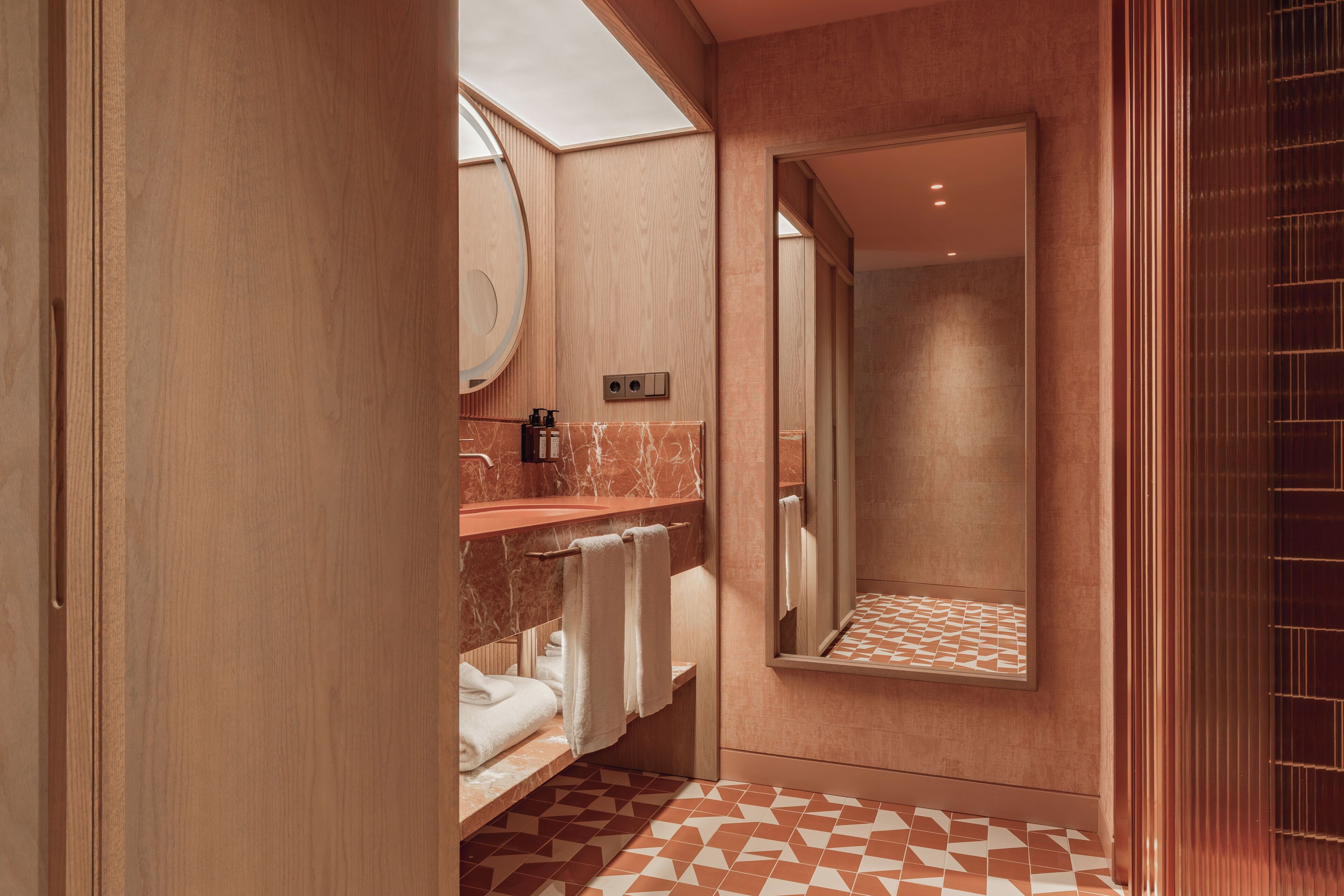 Une salle de bain moderne avec un meuble-lavabo en bois, un miroir et un carrelage décoratif.