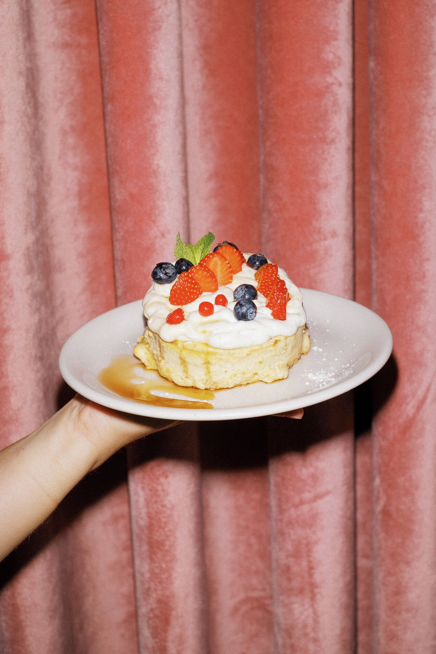 A dessert on a plate with a hand holding it.