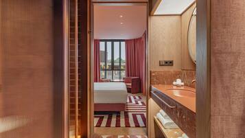 Een hotelkamer met een bed, een badkamer met een wastafel en spiegel, en uitzicht naar buiten.