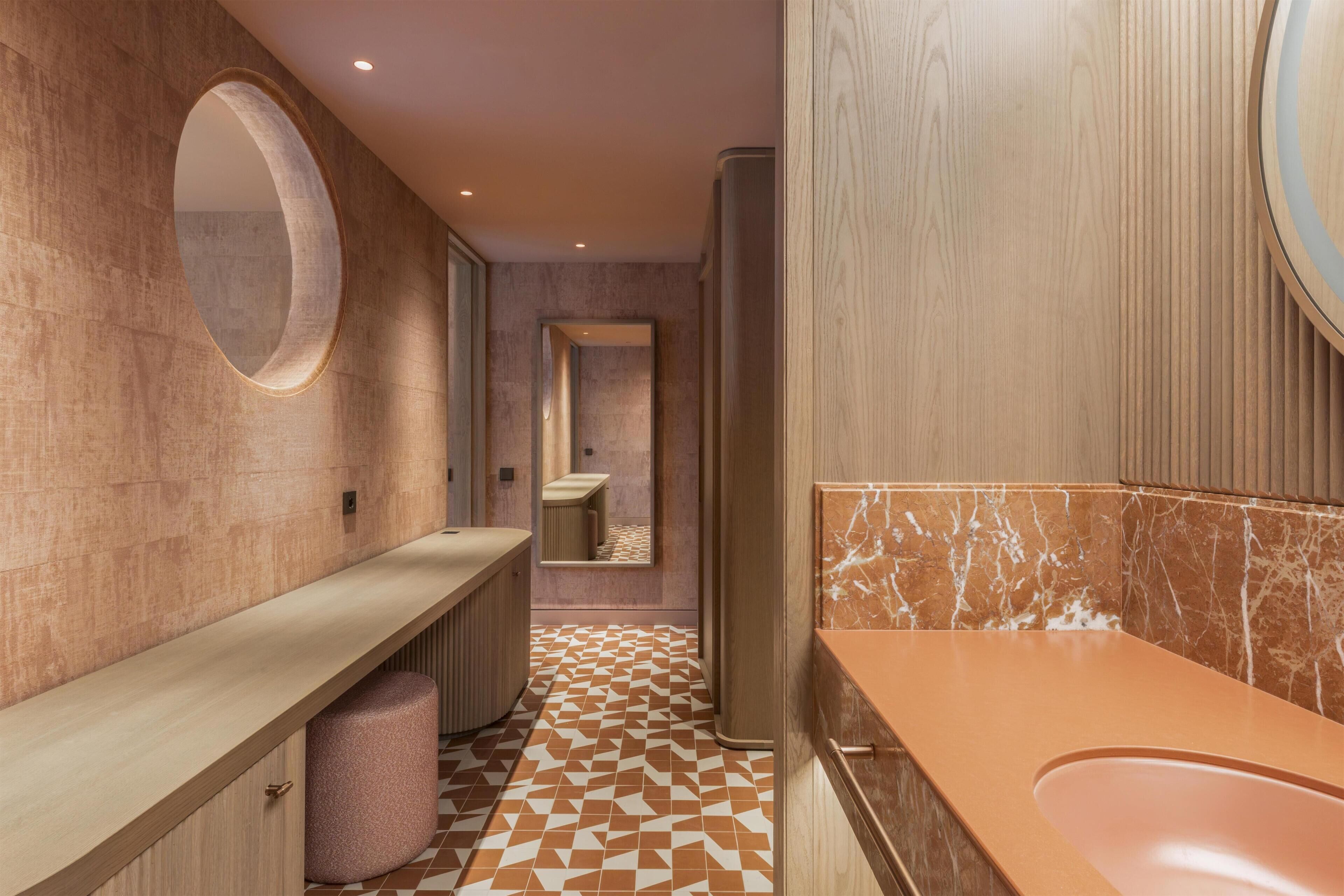 A modern bathroom with a marble vanity, a round mirror, and a patterned floor.
