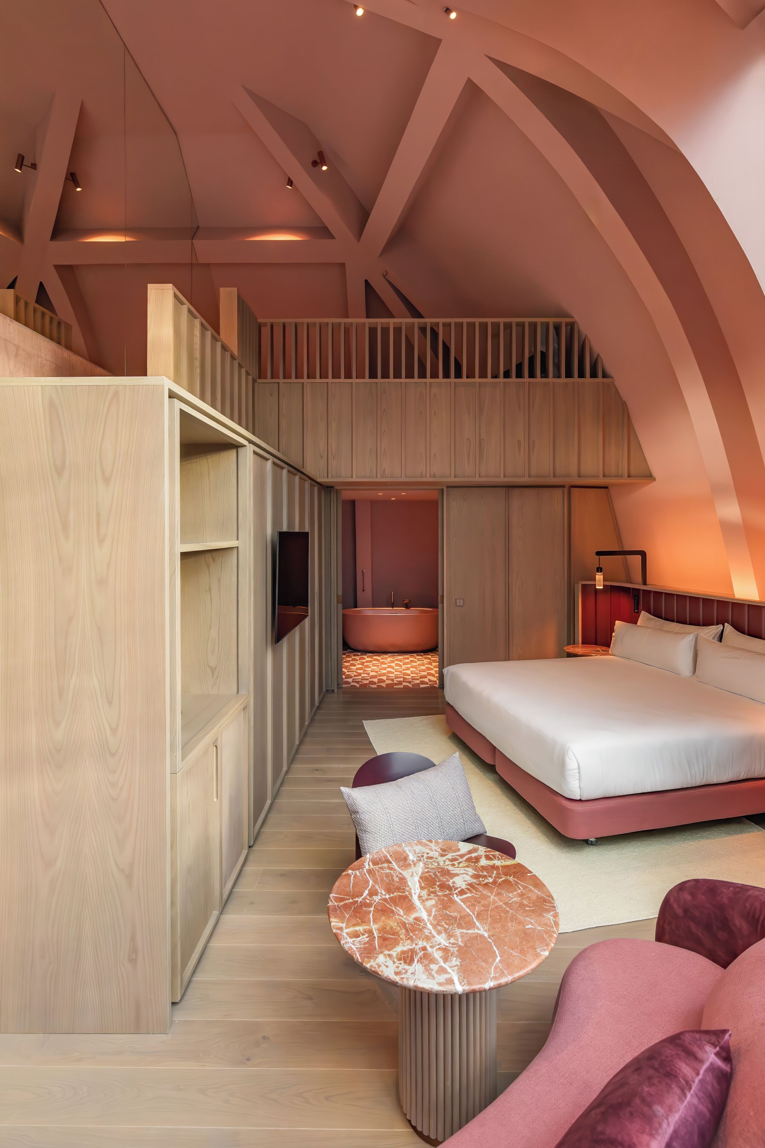 A modern interior with a loft bedroom, a sitting area, and a bathroom.