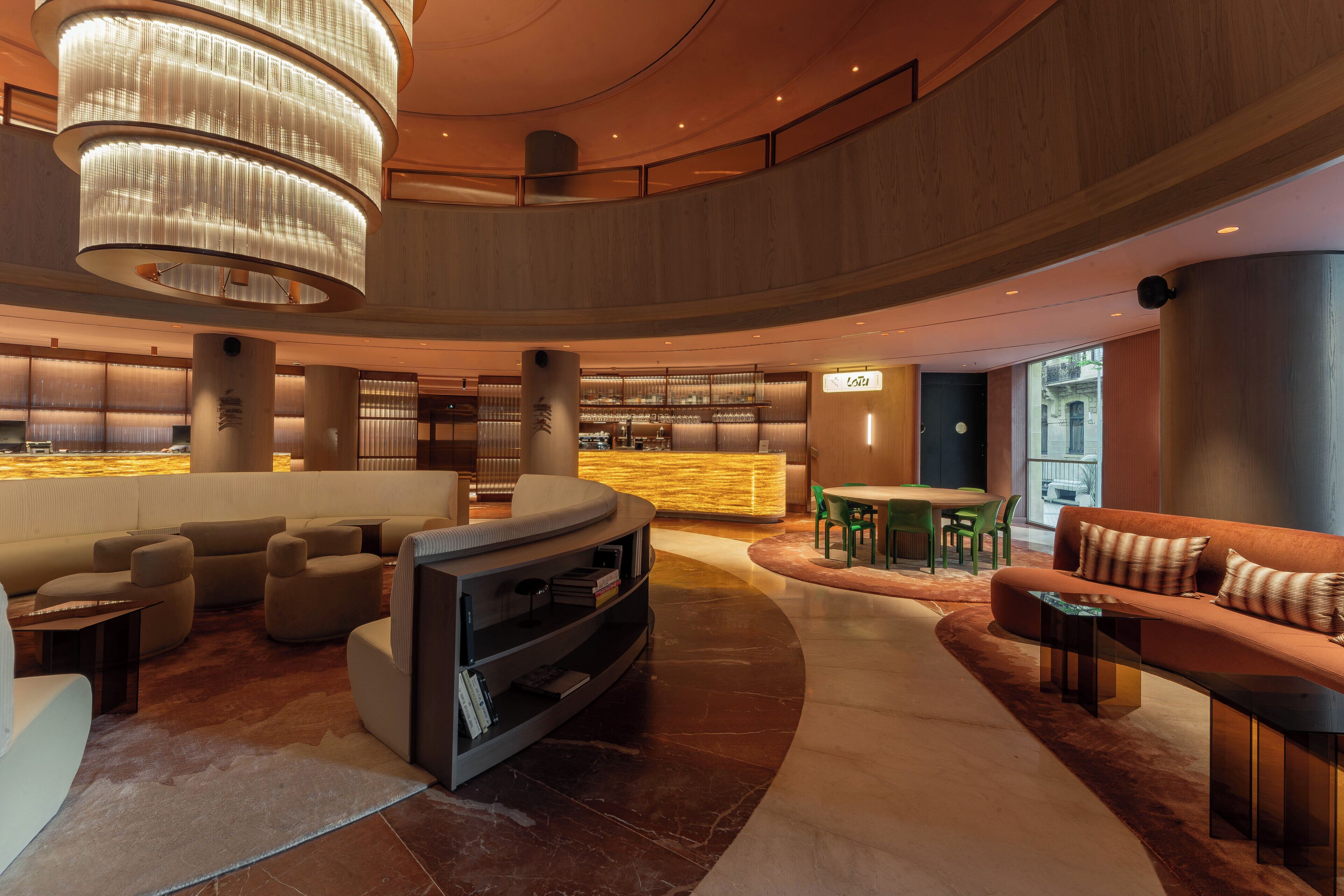 A modern lobby with a curved seating area, a bar, and a reception desk.