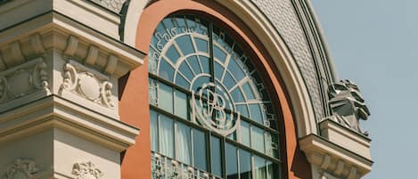 A building with a large arched window, ornate architectural details, and a statue on the roof.