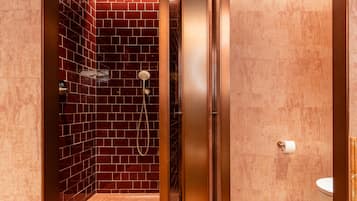 Een badkamer met een douche, toilet en wastafel.