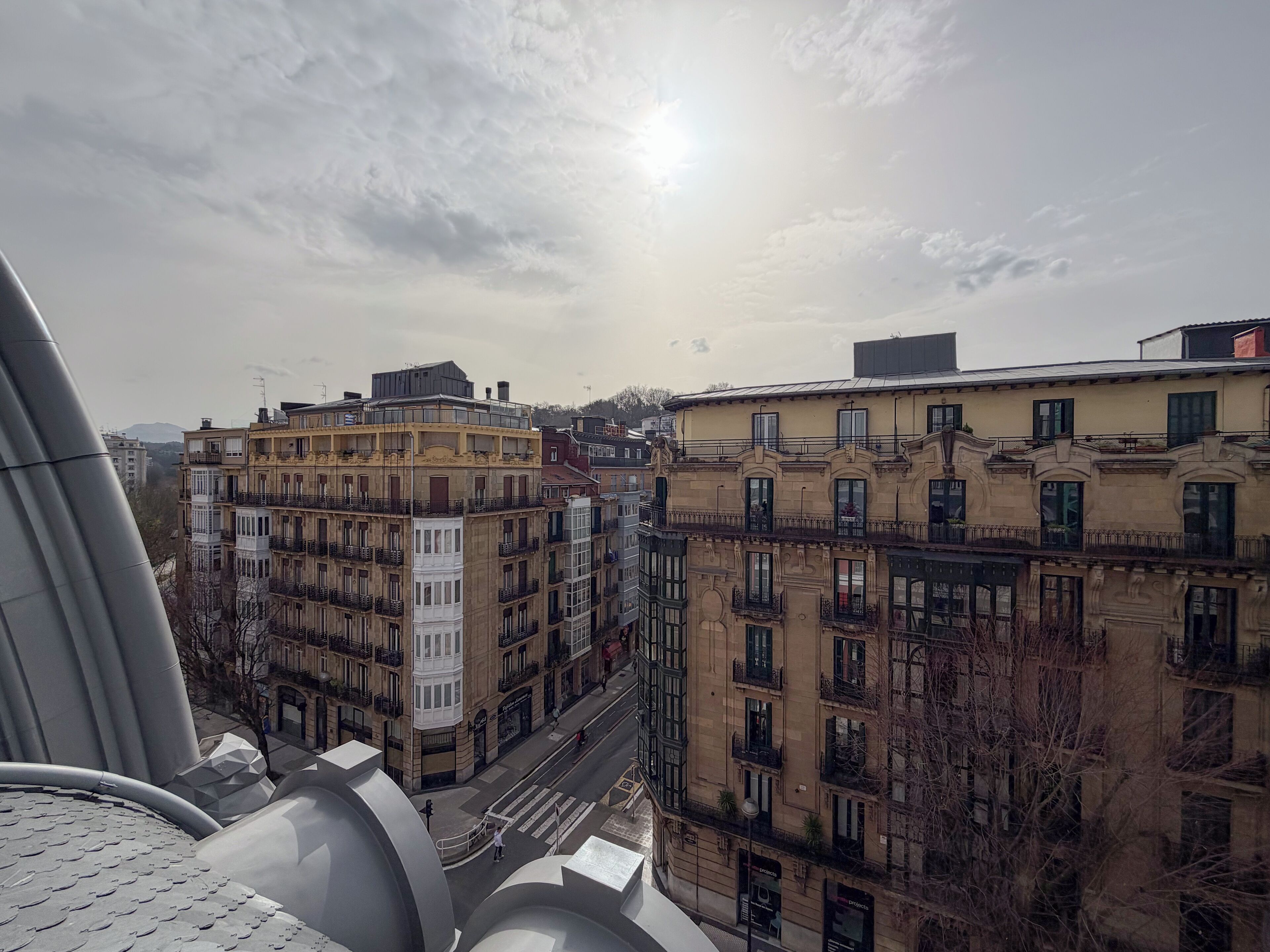 A cityscape with multi-story buildings, a street, and a clear sky.