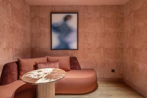A modern room with a curved sofa, a round table, and a framed artwork on the wall. - Hotel Palacio Bellas Artes San Sebastián, Curio Collection by Hilton (San Sebastián)