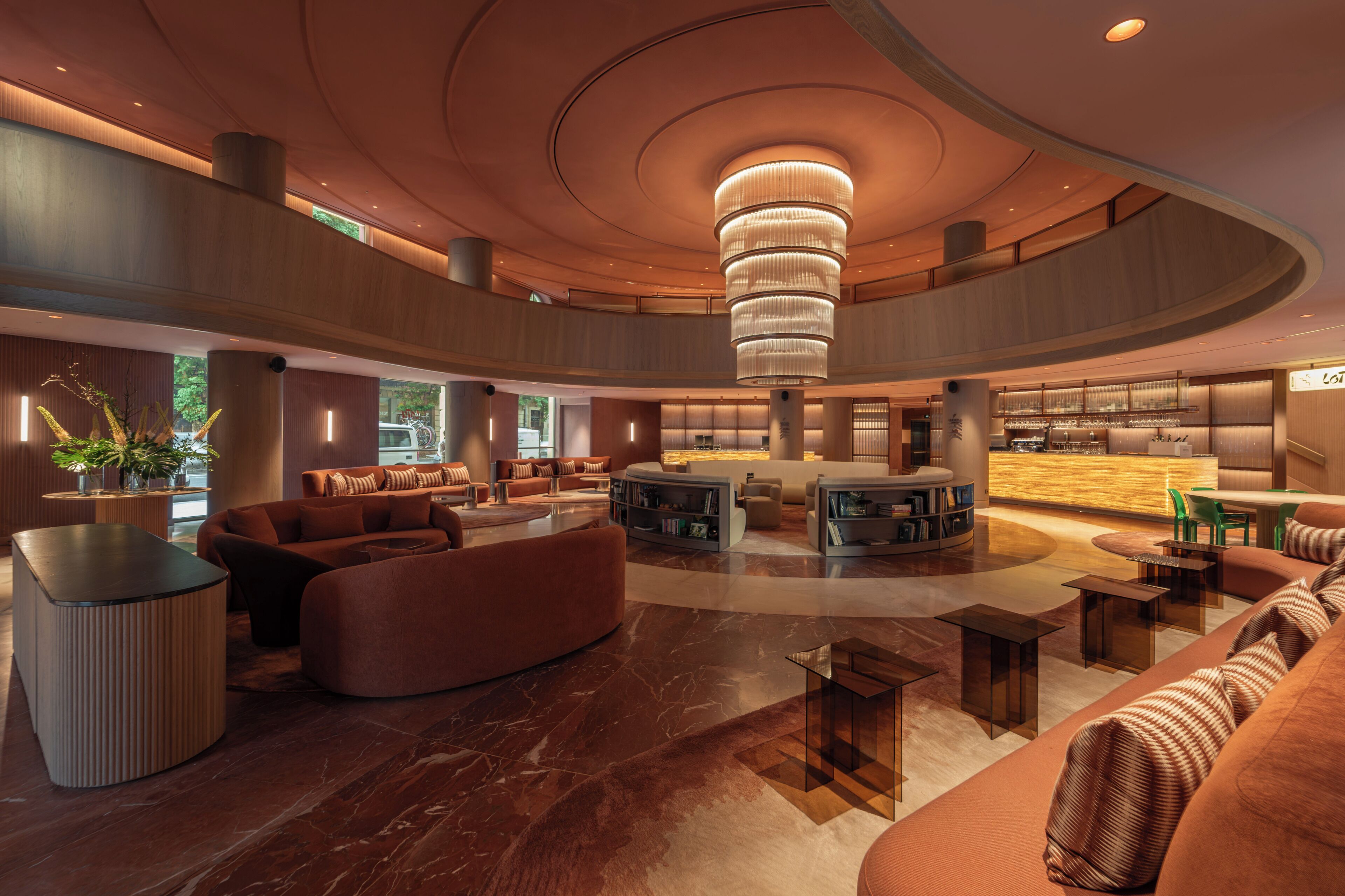 A spacious lobby with a central seating area, a bar, and a large chandelier.