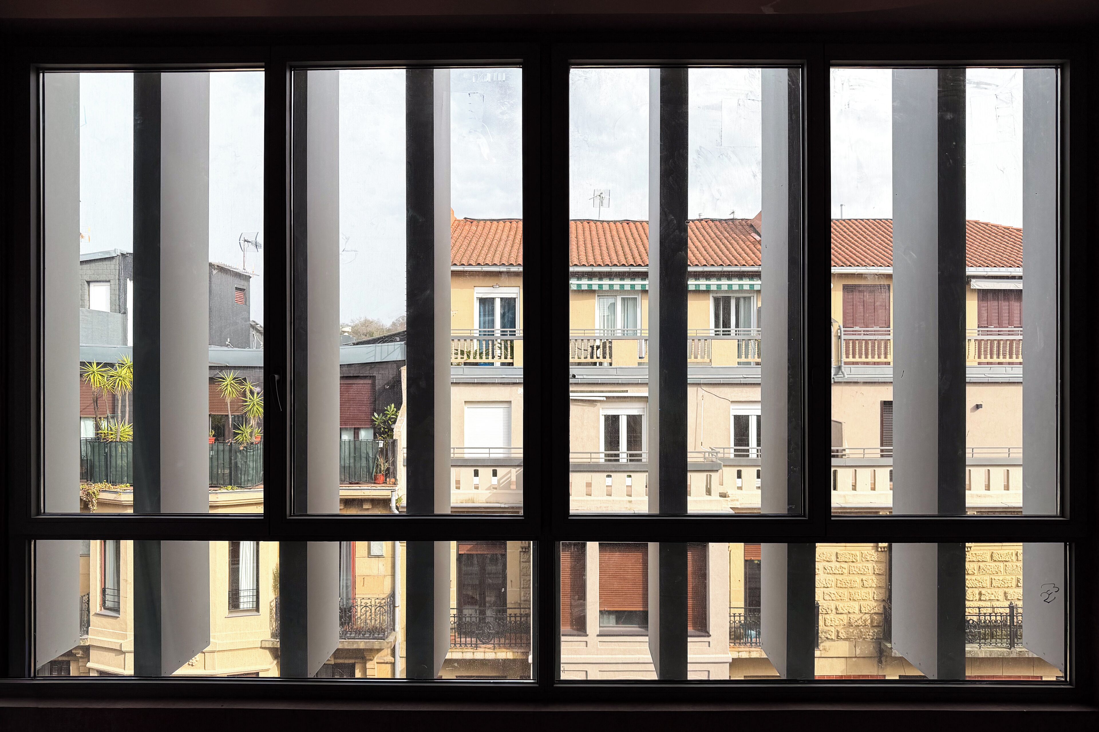 Una ventana con varios paneles, cada uno mostrando vistas de edificios residenciales con balcones y barandillas.