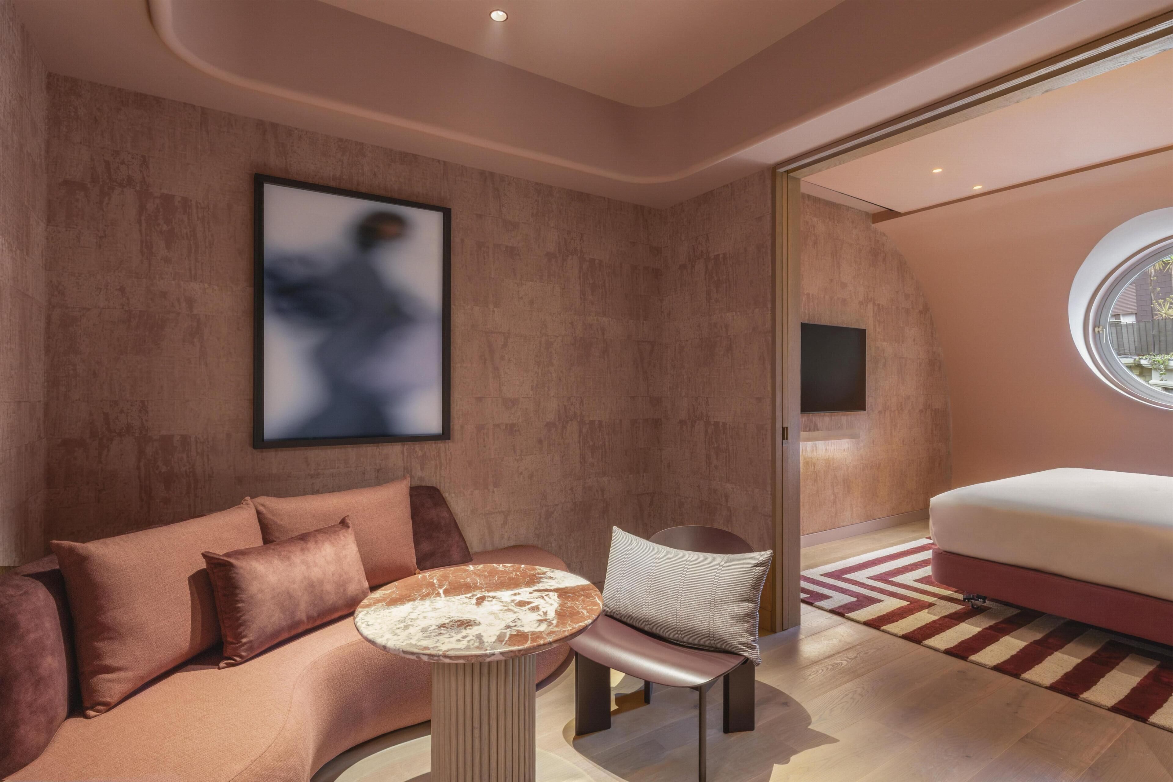 A modern interior with a sofa, a round table, a chair, and a bed.