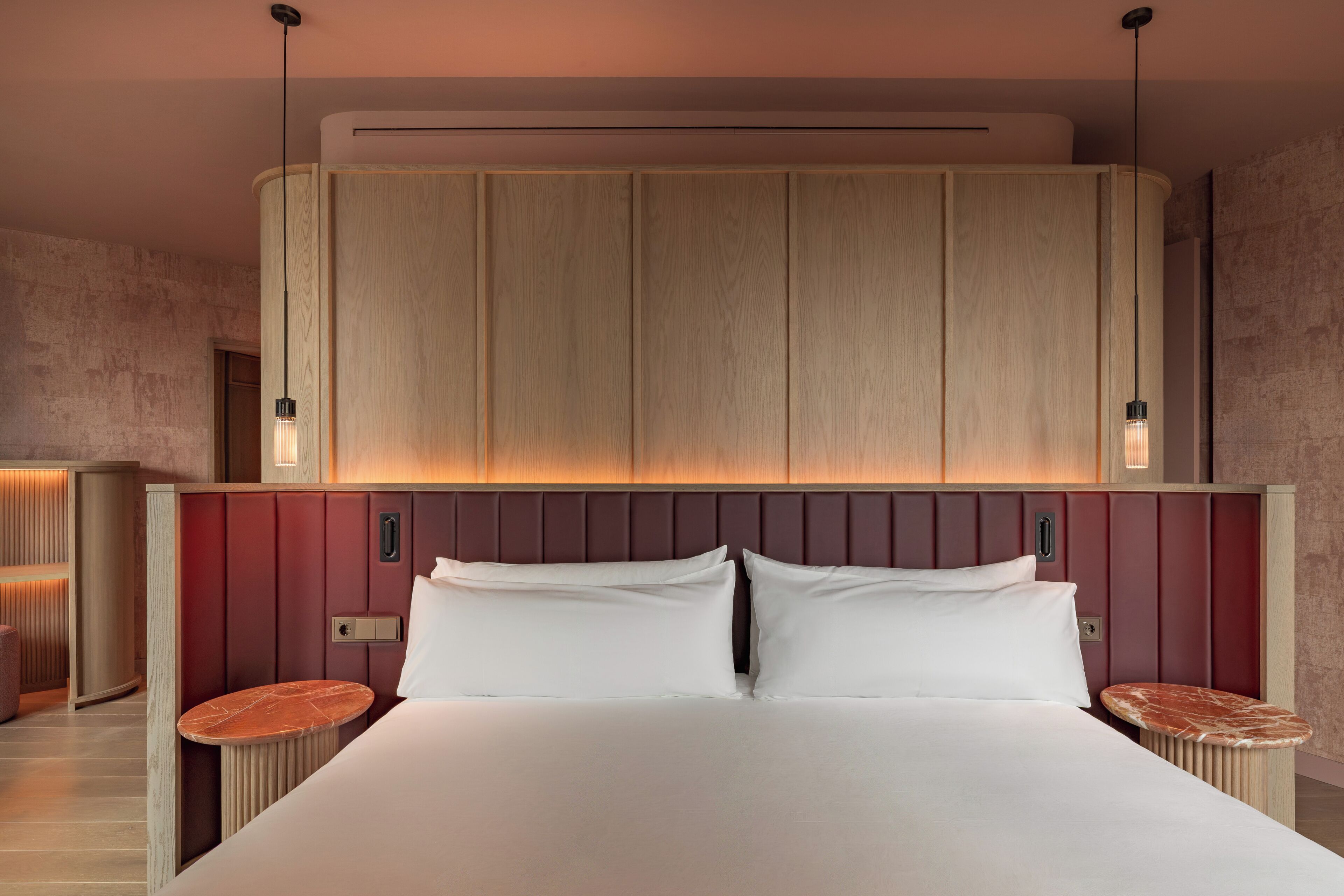 A hotel room with a large bed, wooden headboard, and two bedside tables.