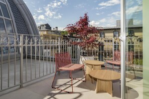 A balcony with metal railings, a red chair, and two round wooden tables. - Hotel Palacio Bellas Artes San Sebastián, Curio Collection (San Sebastian)