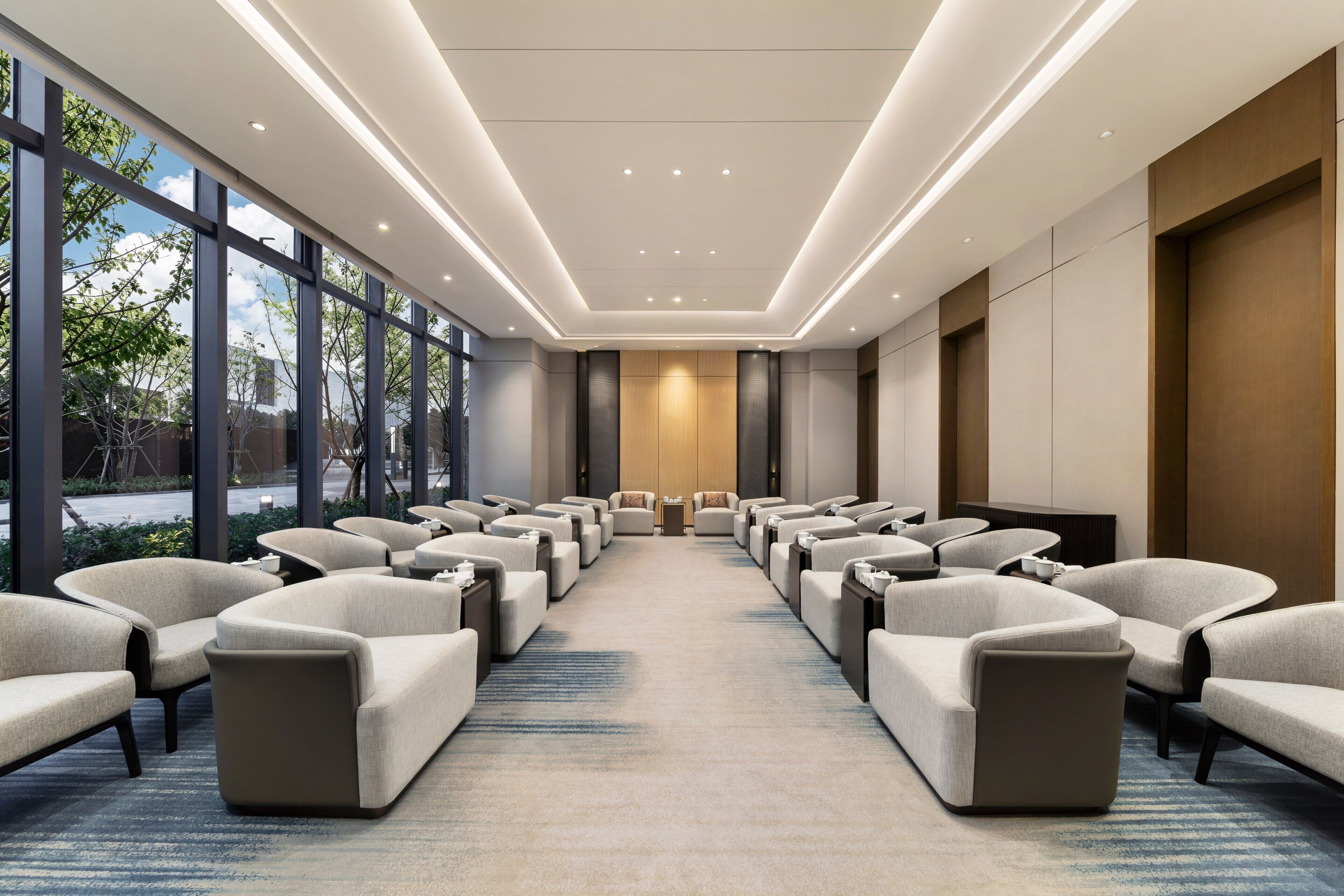 A conference room with rows of chairs, a carpeted floor, and large windows.