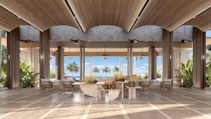 A spacious lobby with a view of the ocean, featuring a central seating area with tables and chairs, and large windows providing natural light. - Hilton Burau Bay Langkawi Resort (Langkawi)
