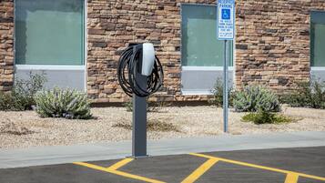 Un área de estacionamiento con una estación de carga para Tesla y un letrero de estacionamiento reservado para vehículos con placas de discapacidad.