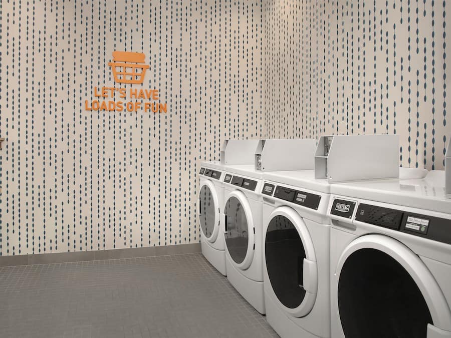 A laundry facility with multiple washing machines and a wall with a pattern of hanging teardrop shapes.