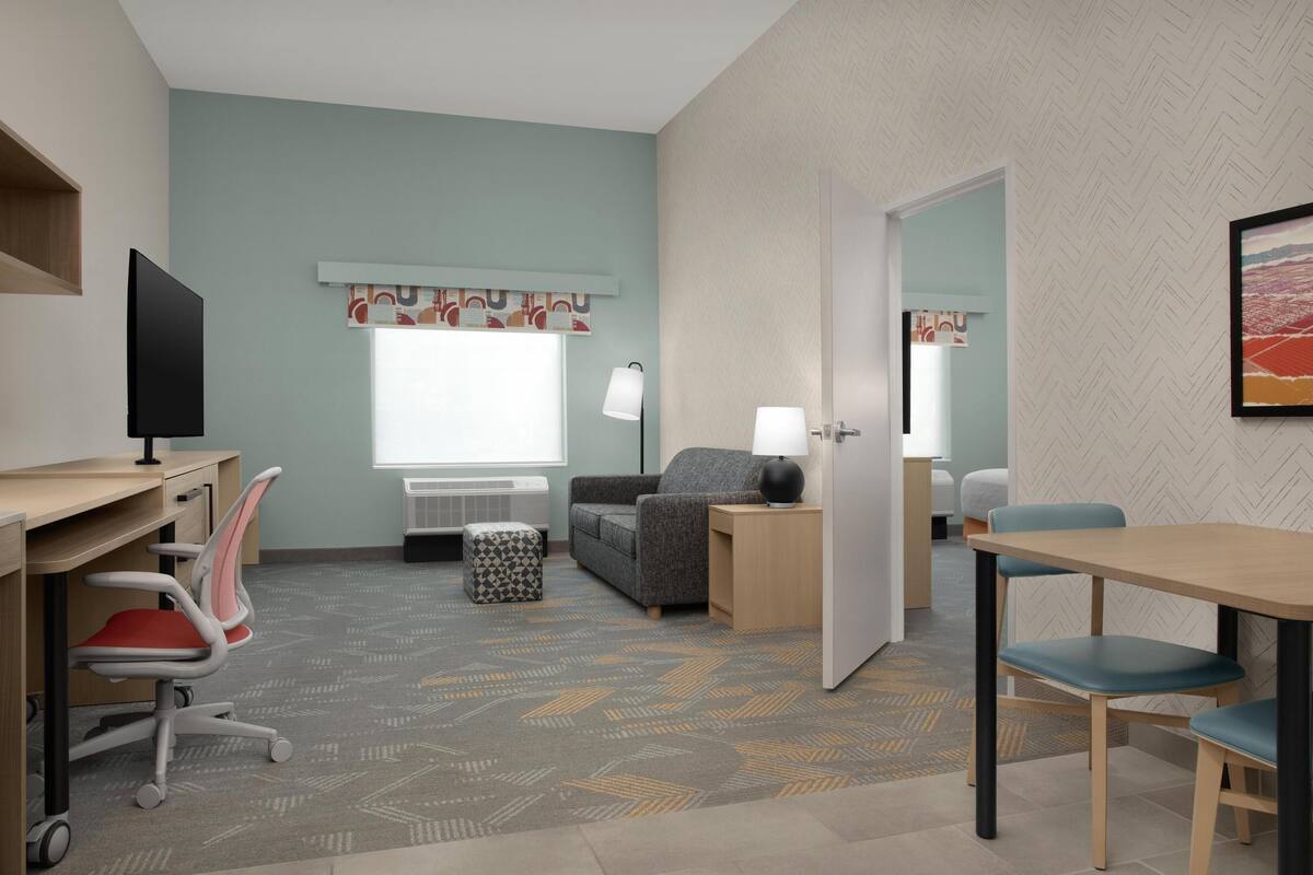 Une chambre d’hôtel équipée d’un bureau, d’un fauteuil de bureau, d’un canapé et d’une table à manger avec des chaises.