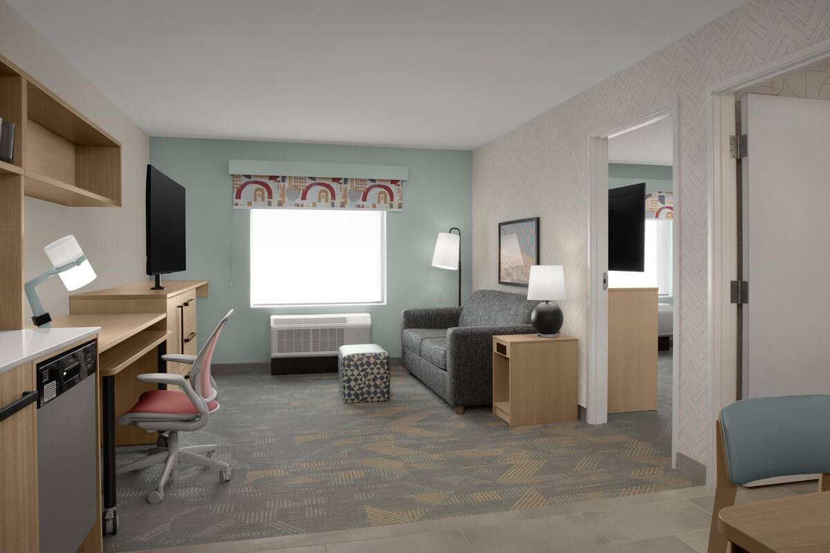 Une chambre moderne équipée d’un bureau, d’une chaise, d’un canapé et d’un téléviseur.