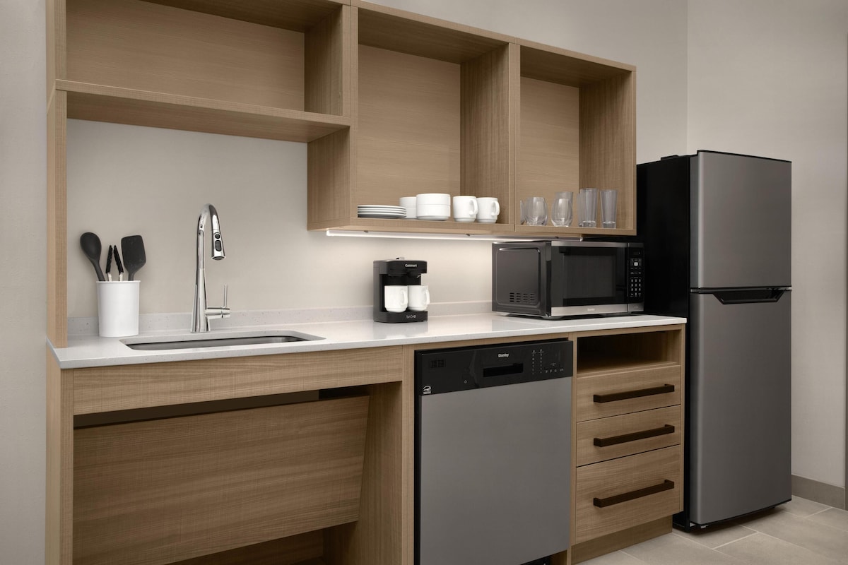 A modern kitchen with a dishwasher, microwave, and refrigerator.