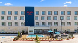 A Hampton Inn by Hilton hotel with a pool area, outdoor seating, and a parking lot. - Hampton Inn By Hilton Wharton (Wharton)