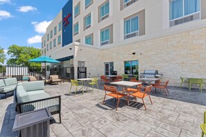 Une cour d’hôtel avec des espaces de détente en plein air, une piscine et un coin barbecue.
