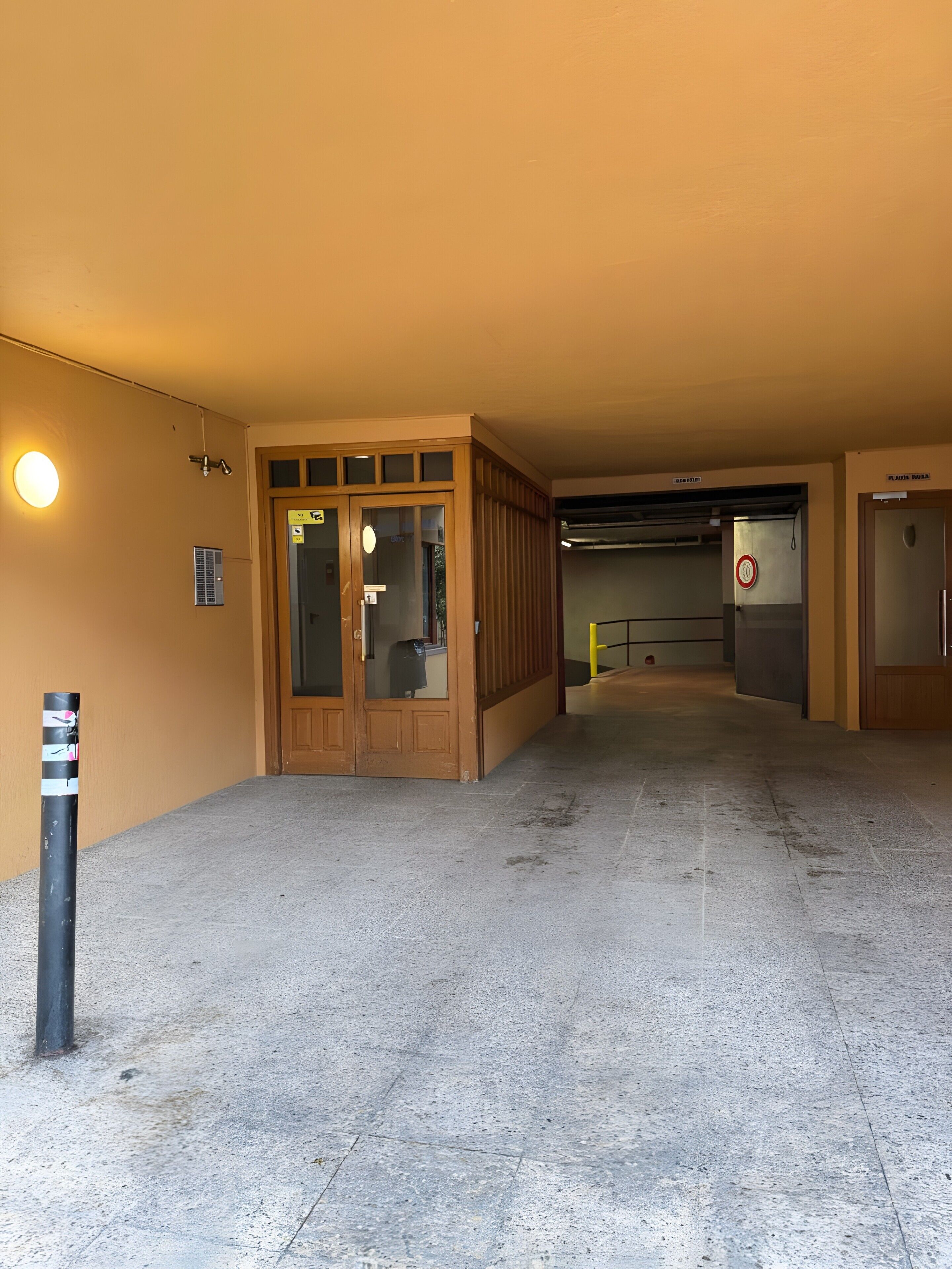 Un couloir avec une porte donnant sur une pièce, une poubelle et un panneau indiquant un espace non-fumeur.