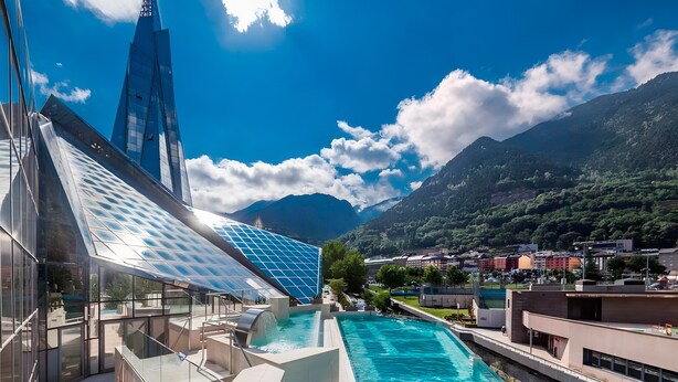 Ein modernes Hotel mit Schwimmbad, Glasfassade und Bergblick.