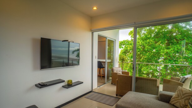 A modern living room with a flat-screen TV, a glass coffee table, and a sofa. - Beachfront Ocean-View Apartment in Gated Community (Parrita)