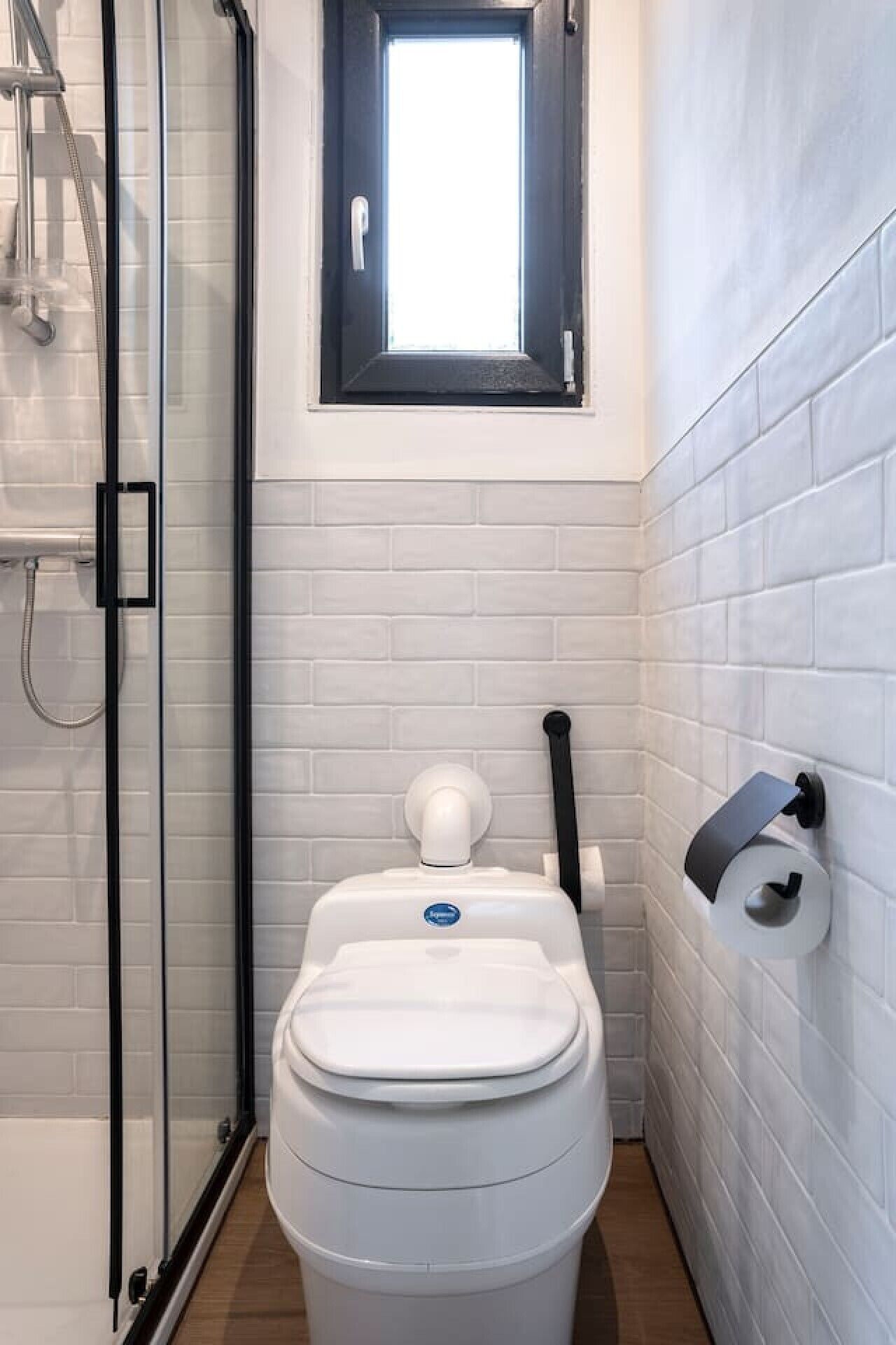 Un baño con inodoro, ducha y ventana.