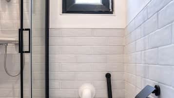 Un baño con inodoro, ducha y ventana.