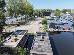 Un port de plaisance avec des bateaux amarrés, une zone sablonneuse et un bâtiment doté d’un toit plat.