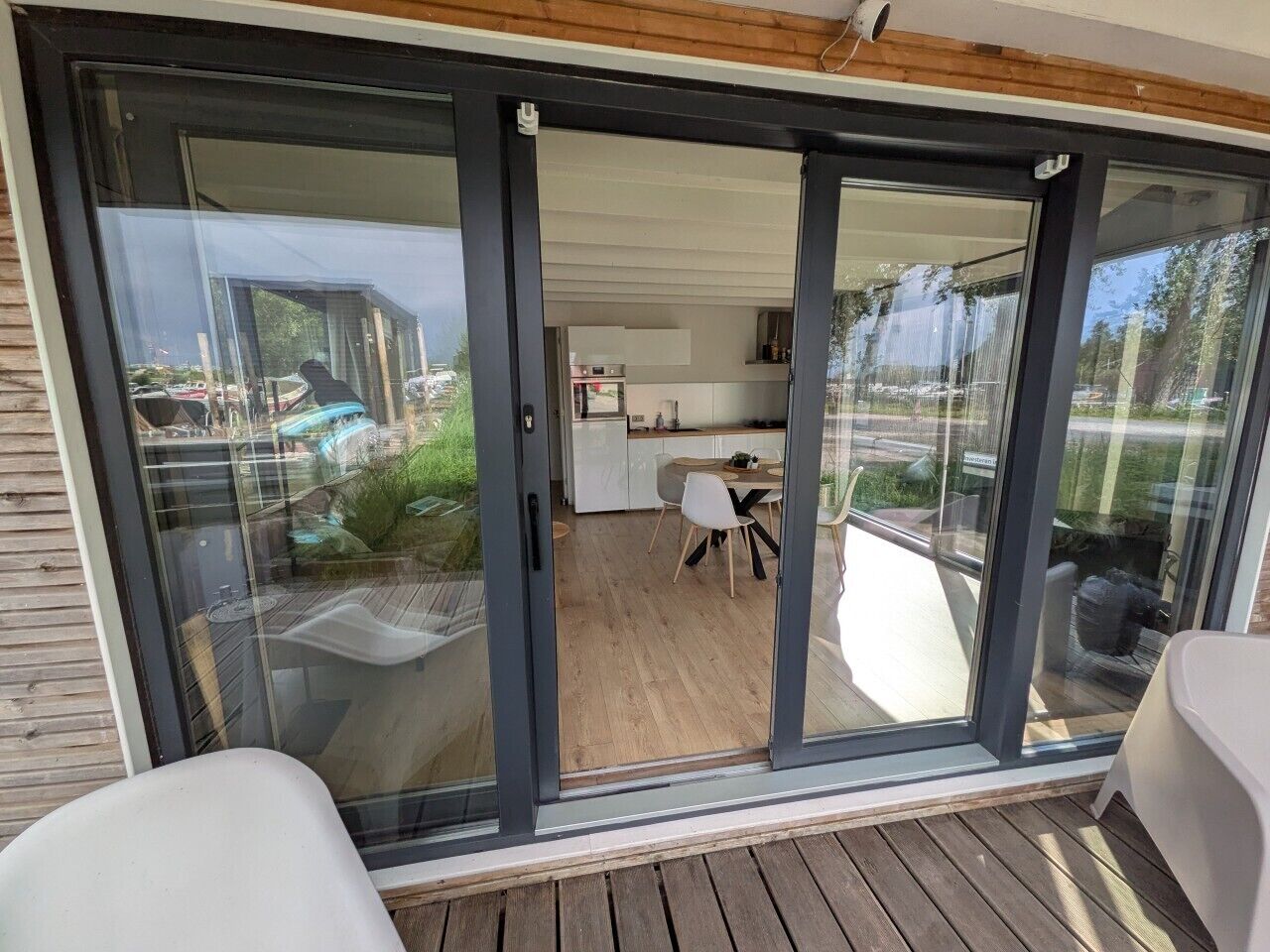 Een schuifdeur die leidt naar een balkon, met een eethoek en een zichtbare keuken binnen.