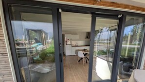 A sliding glass door leading to a balcony with a dining area and a kitchen visible inside. - 6-persons Houseboat Experience in Amsterdam (Amsterdam)