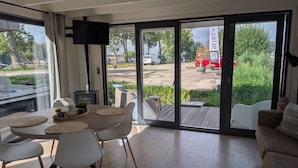 A modern interior with a dining area, a sofa, and a large sliding glass door leading to an outdoor space. - 6-persons Houseboat Experience in Amsterdam (Amsterdam)