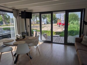 Een modern interieur met een eethoek, een bank en een grote schuifpui naar buiten.