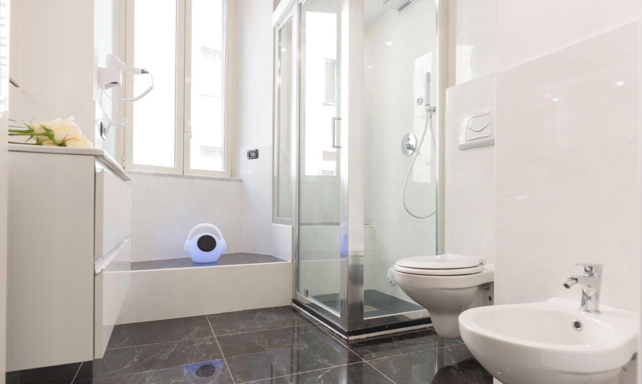 A modern bathroom with a glass shower enclosure, a toilet, and a sink.